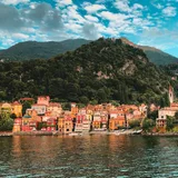 A colourful European waterfront village beneath green hills