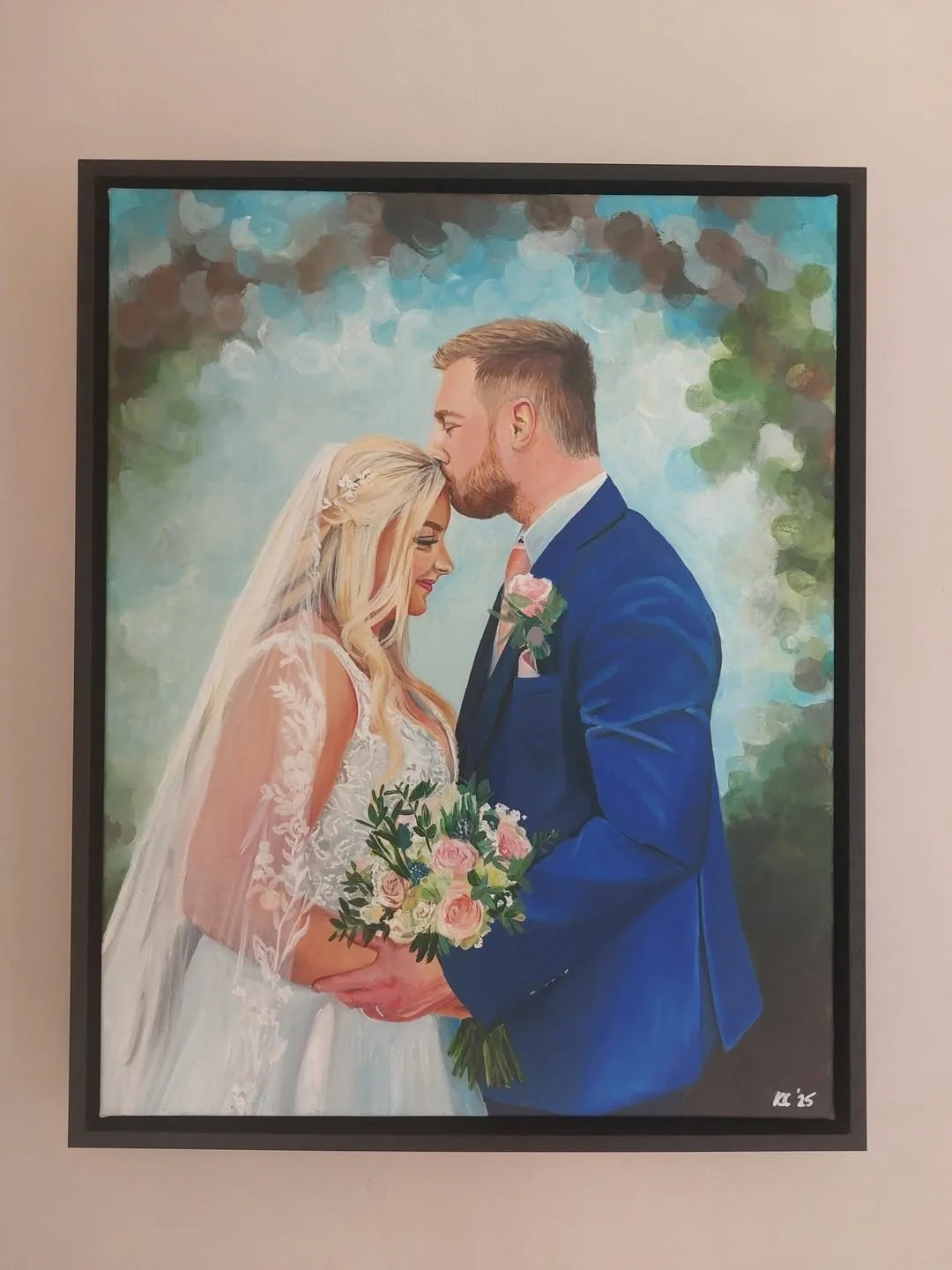 A framed wedding portrait of a groom kissing his bride on the forehead as she holds her bouquet.