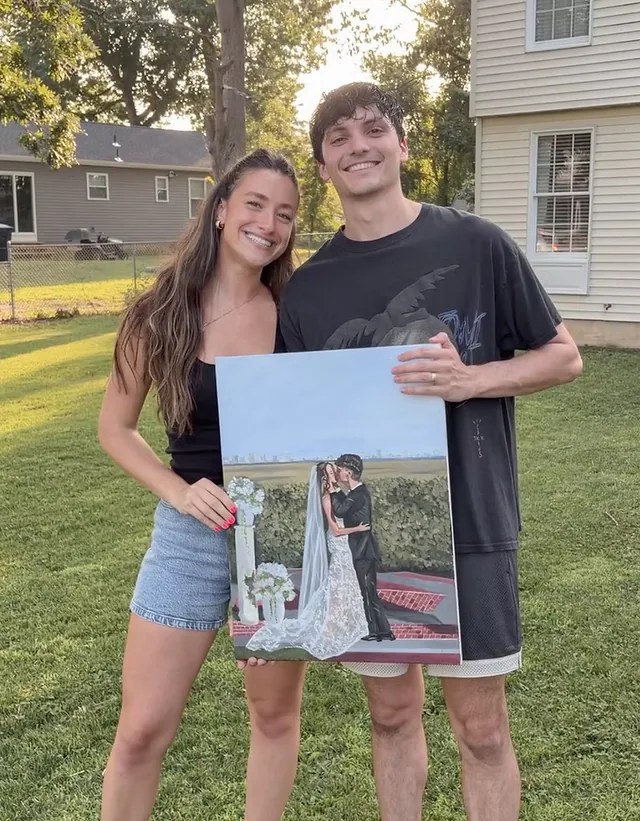 Young couple holding their painted wedding portrait outdoors