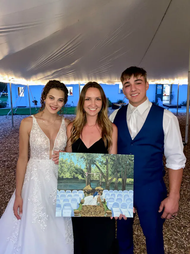 Artist and newlyweds holding their finished landscape wedding painting