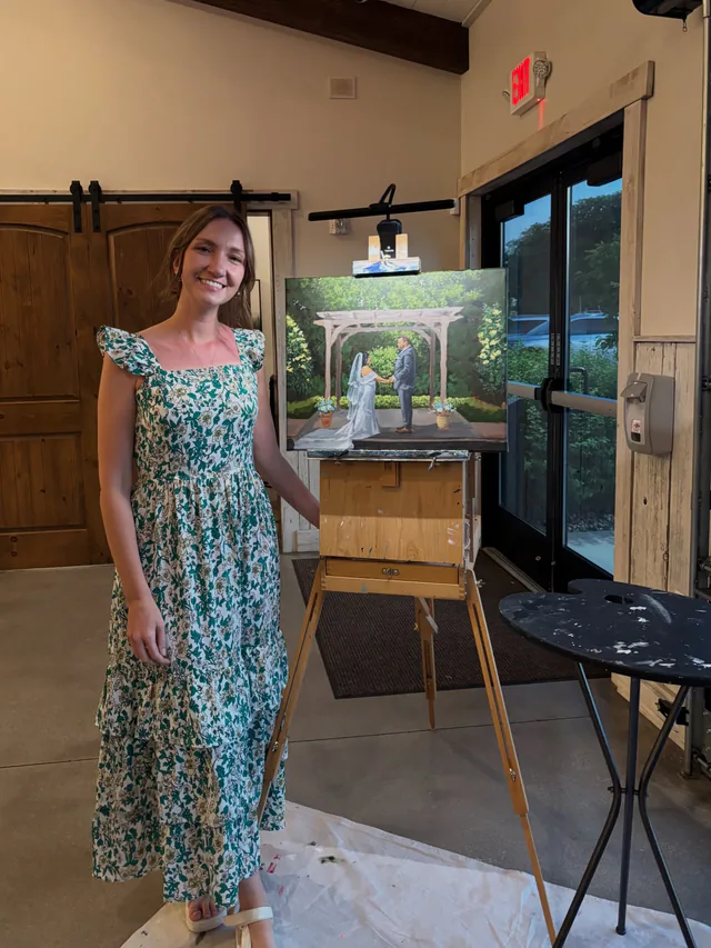 Wedding artist beside her live ceremony painting on an easel