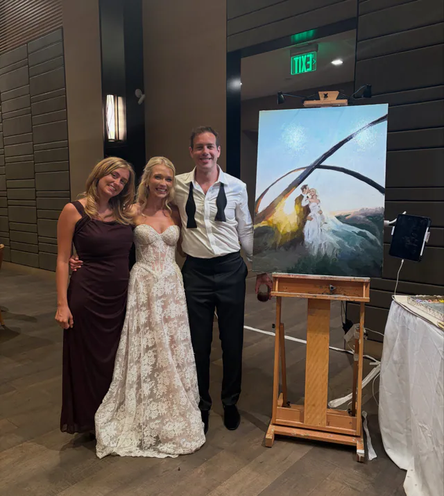 Artist and newlyweds beside an expressive live wedding painting