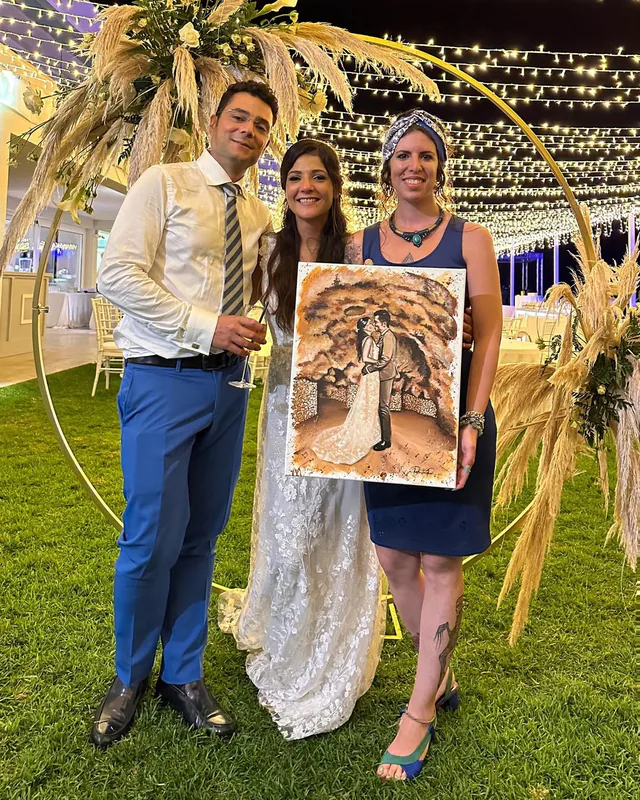 Artist and newlyweds holding a finished wedding portrait