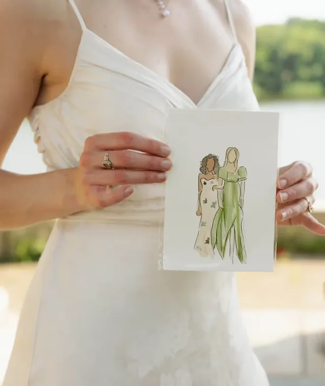 Bride holding a bespoke illustration of two wedding guests