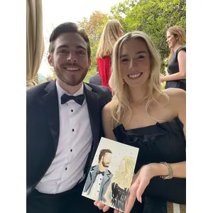 Smiling wedding guests in formalwear holding their finished live watercolour portrait.